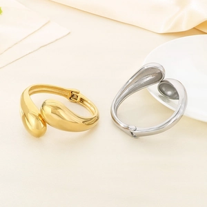 Detail of gold and silver irregular fluid bangles with polished finish and side hinge