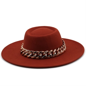 Close-up of wine red wool felt fedora with decorative chunky gold chain on white background