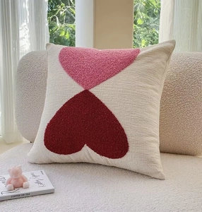 Detail of embroidered layered heart patterns on a beige textured cotton linen pillow cover