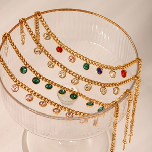 Détail d'une gourmette dorée aux pierres circulaires colorées sur décor en verre
