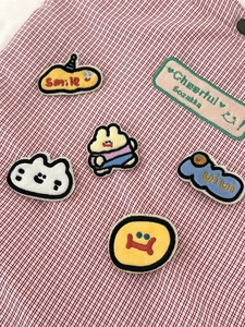 Set of colorful embroidered cartoon patches on a red and white checkered fabric background