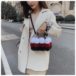 Detail of red and black faux fur handbag with shoulder strap on a model outfit