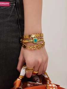 Detailed shot of retro gold bracelets set with turquoise and red stone rings on denim