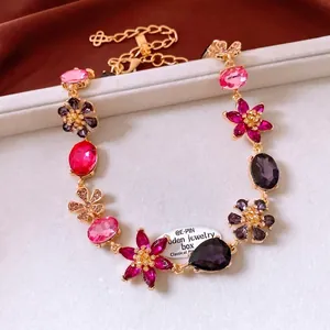 Vintage gold necklace with colorful crystal flower charms and purple gems on grey velvet