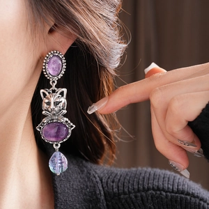 Detail of vintage cat earrings featuring purple gemstones and gradient beaded drops