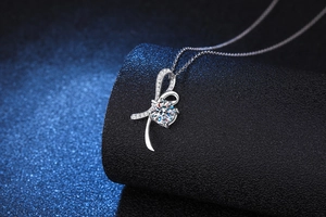 Close-up of S925 silver bow pendant featuring a 1 carat round moissanite with small diamonds