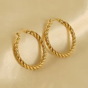 Vintage 18K gold-plated twisted oval hoop earrings on elegant silk background