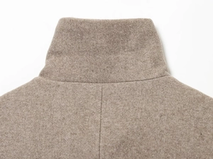Vue détaillée de la texture en laine camel et des coutures du col montant au dos de la veste