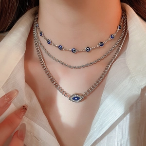 Close-up of triple-layered silver necklace featuring diamond-encrusted blue evil eye pendants