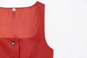 Macro shot of red vest neckline with dark button detail and size M label
