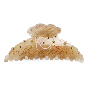 Macro view of marbled brown hair claw with Moonchild script and rhinestone details