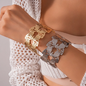 Detailed close-up of textured hollow butterfly metallic arm cuff on model's wrist