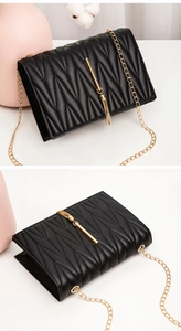 Detail of black quilted crossbody bag with golden chain and tassel pendant