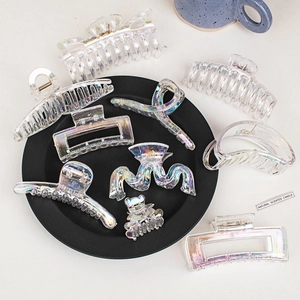 Macro shot of iridescent acrylic hair claws in rectangular and wavy shapes on a black tray