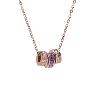 Détail du collier en or rose avec trois anneaux rotatifs sertis de cristaux colorés
