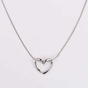 Detailed close-up of a silver hollow heart pendant on a minimalist snake chain necklace