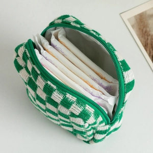 Close-up of green and white checkered knit pouch showing zipper and storage capacity