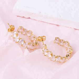 Detailed view of gold C-shaped earrings with inlaid clear oval-shaped zircon stones