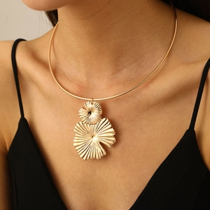 Detail of vintage gold textured petal pendant on a choker necklace worn by a model