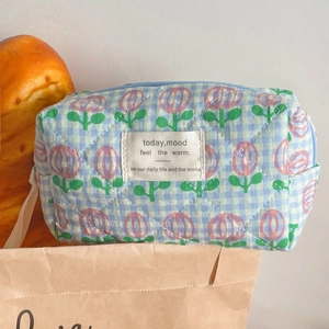 Detail view of blue checkered quilted makeup bag with pink tulip pattern and top handle