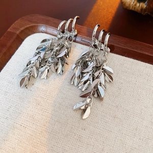 Macro detail of silver wheat ear tassel earrings with layered metallic leaf charms