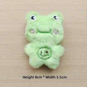 Detail of a plush light green frog toy with embroidery, measuring 8cm high and 5.5cm wide