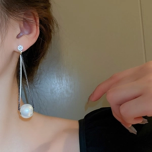 Detail of long tassel earrings featuring zircon studs and white pearls on a model