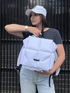 Vue détaillée d'un sac à dos matelassé blanc avec de grands carreaux et sangles noires