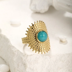Detailed macro view of gold-plated ring with turquoise stone and hammered texture