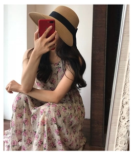 Close-up of a pink floral maxi dress paired with a woven straw hat featuring black ribbon