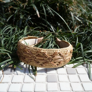 Detail of handwoven raffia headband showing intricate floral patterns and natural texture