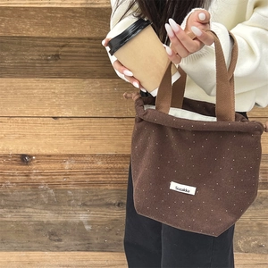 Close-up of brown wool drawstring handbag with white polka dots and dual handles