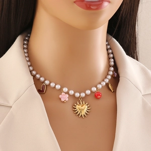 Gros plan détaillé d'un collier de perles fantaisie avec pendentifs émaillés et cœurs dorés