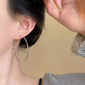 Close-up of silver twist hoop earrings worn by a model for a minimalist fashion look
