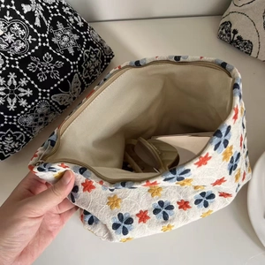 Detailed embroidery texture on ivory canvas cosmetic bag featuring colorful flower patterns