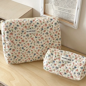 Quilted floral corduroy makeup bags in beige set on a rustic wooden tabletop