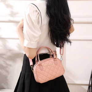 Pink quilted shoulder bag with gold metal logo and adjustable strap shown on model