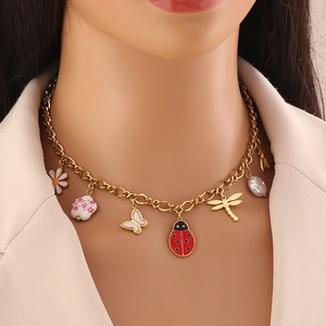 Gold stainless steel necklace with ladybug, butterfly, and daisy charms worn by a model