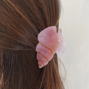 Pink conch shell hair claw clip with marble texture shown on deep brown hair