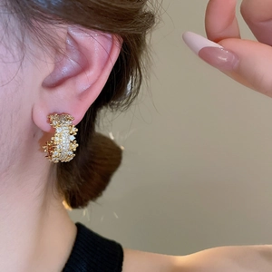 Close-up of elegant gold C-shaped earrings with shimmering cubic zirconia on model ear