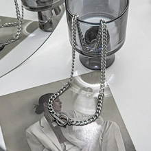 Detail of silver Cuban link necklace with T-bar clasp draped over a stylish glass