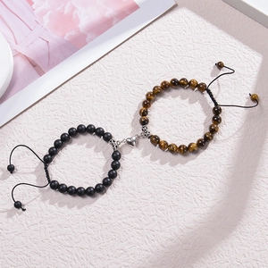 Magnetic heart couple bracelets with black matte and tiger eye beads on a beige background