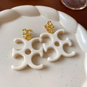 Detail view of vintage cream floral earrings on a ceramic dish with golden metal accents
