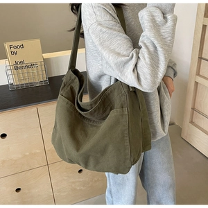 Detail view of olive green canvas tote bag showing side pockets and wide shoulder straps