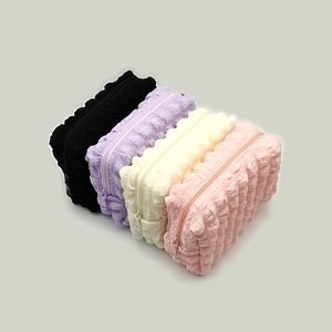 Close-up of textured bubble makeup bags in black, purple, cream, and pink with zippers