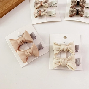 Detail view of plaid and satin bow hair clips in khaki and brown on display card