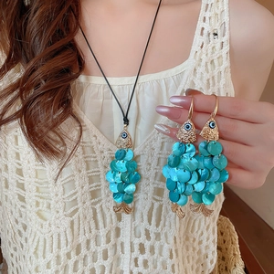 Detailed view of the fish pendant featuring blue shell scales and an evil eye charm