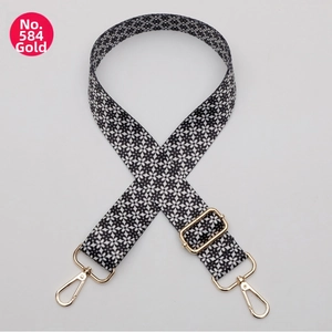 Detail of adjustable polyester bag strap with black-white floral pattern and gold hardware