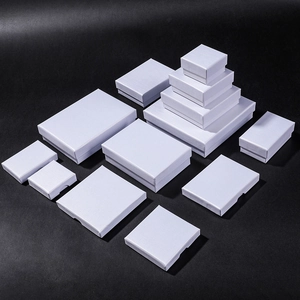 Various sizes of white textured jewelry gift boxes for rings and necklaces on black backdrop