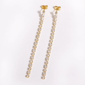 Macro detail of long gold tassel earrings featuring brilliant white zircon stones